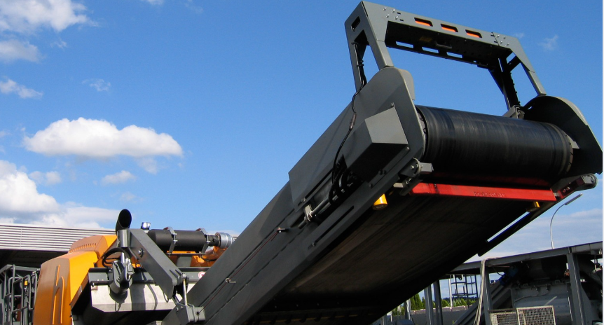 Sensor volumétrico Sensortechnik instalado en cinta de transporte industrial, ubicada en faena minera